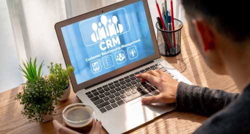 Laptop image with a person using CRM in it indicating Dynamics 365 Support Services 